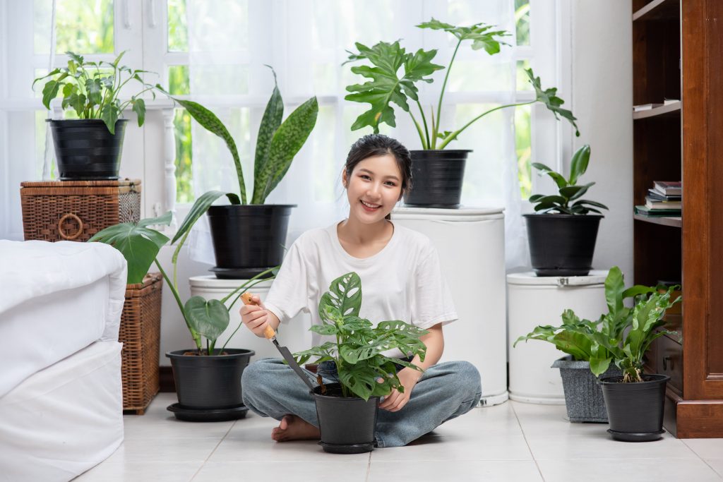 Mujer posando con plantas en una habitación |