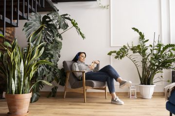 Mujer en sofá rodeada de plantas